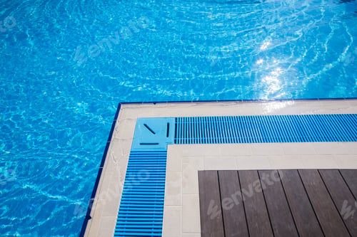 Preview: Beautiful swimming pool with vibrant blue water and modern decking at a sunny outdoor location