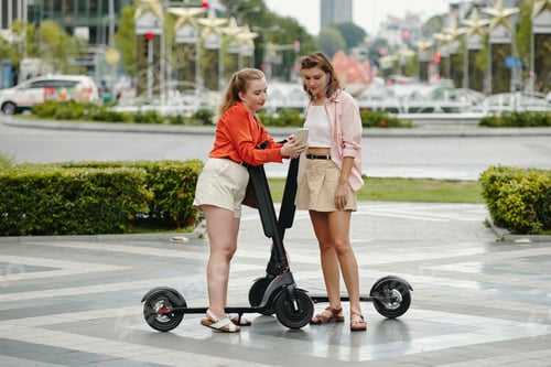 Preview: Pair of Women Riding Electric Scooters in Urban Environment