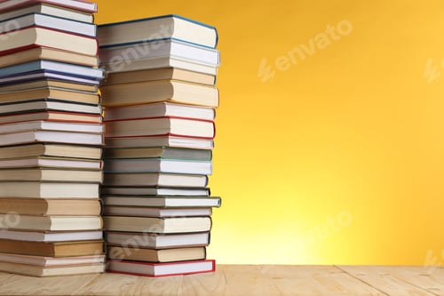 Preview: Many stacked books on table against yellow background. Space for text