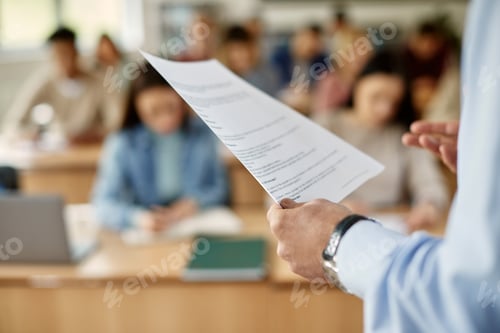 Preview: Close-up of professor reading form paper while giving lecture in the classroom.