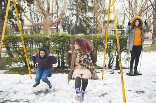 Preview: group of young multiracial women having fun on the swing in play area