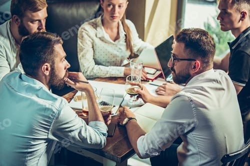 Young cheerful people smile and gesture while relaxing in pub.