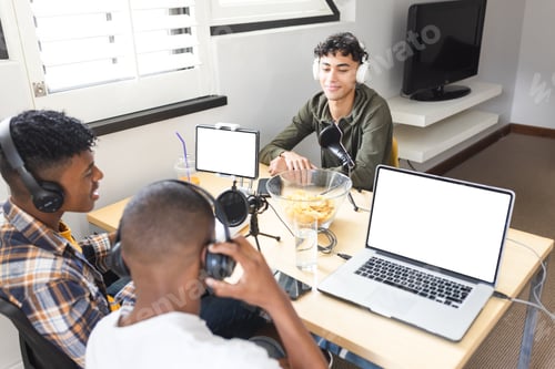 Preview: Image of happy diverse teenage boys with headphones and laptops with copy space at home