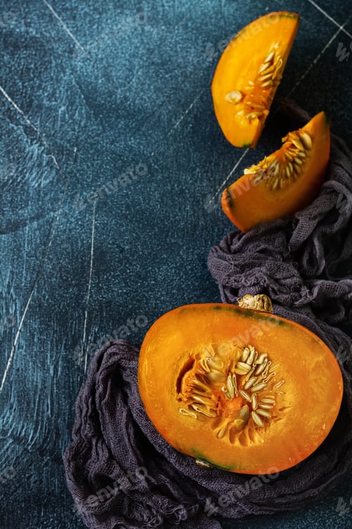 Preview: Fresh cut in half pumpkin with gray napkin on old stone dark blue background. Halloween concept. Top