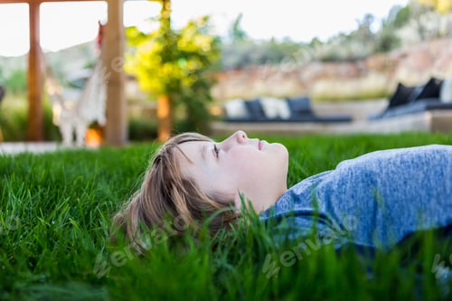 Preview: portrait of smiling 6 year old boy lying down in green grass