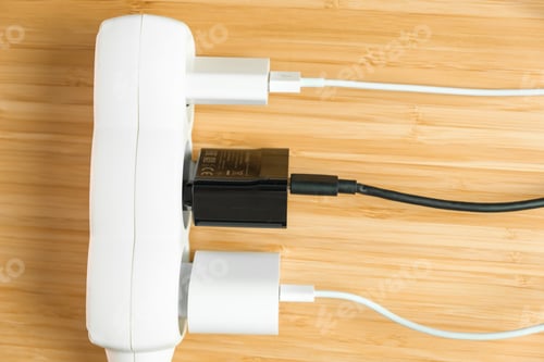 Preview: The electrical extension strip with connected white and black power plugs on the wooden table. Smart