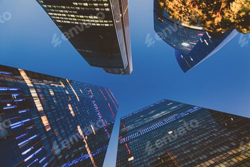 Preview: Looking up at skyscrapers against dark blue sky at night