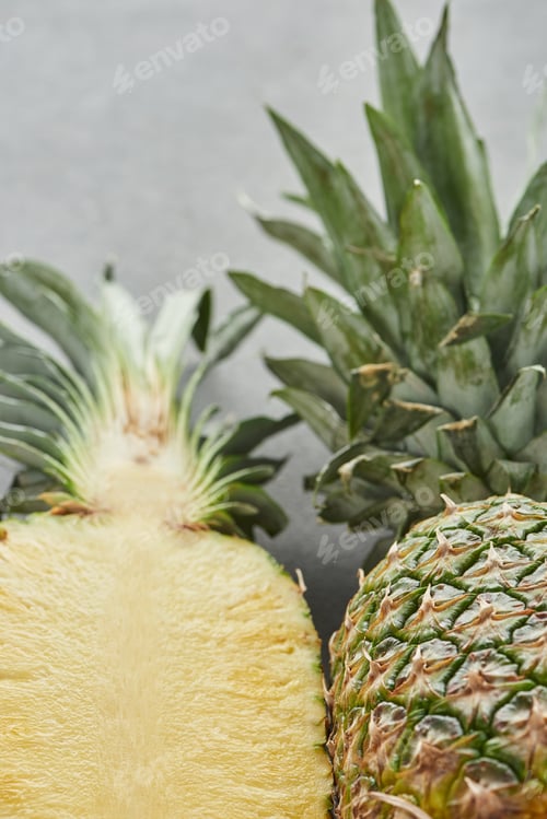 Preview: selective focus of whole and half of pineapple on grey background