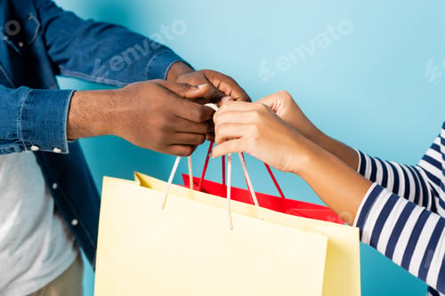 Preview: cropped view of african american man giving shopping bags to wife on blue