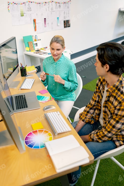 Preview: Caucasian male and female graphic designer discussing over computer at desk