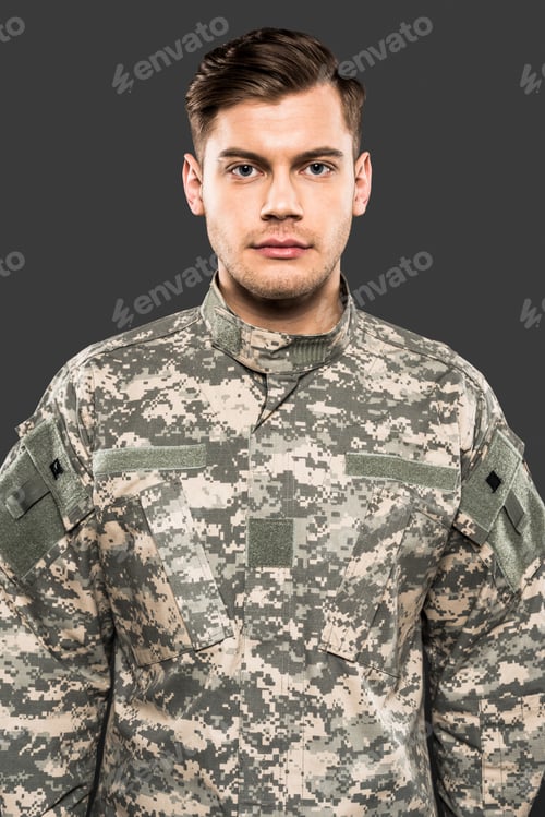 Preview: serious soldier in uniform looking at camera isolated on grey