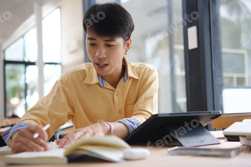 Preview: Student studying online and preparing for exams with digital devices and books