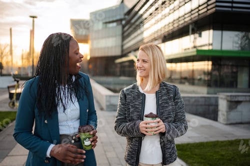 Preview: Diverse businesswomen walking, talking, drinking coffee on urban break