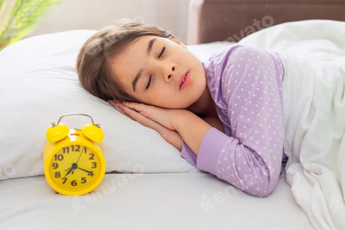 Preview: A cute brunette schoolgirl girl sleeps on a white pillow, on a bed