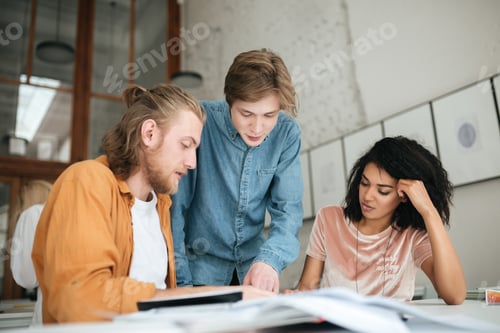 Preview: Two boys with blond hair and girl with dark curly hair working together on new project in classroom