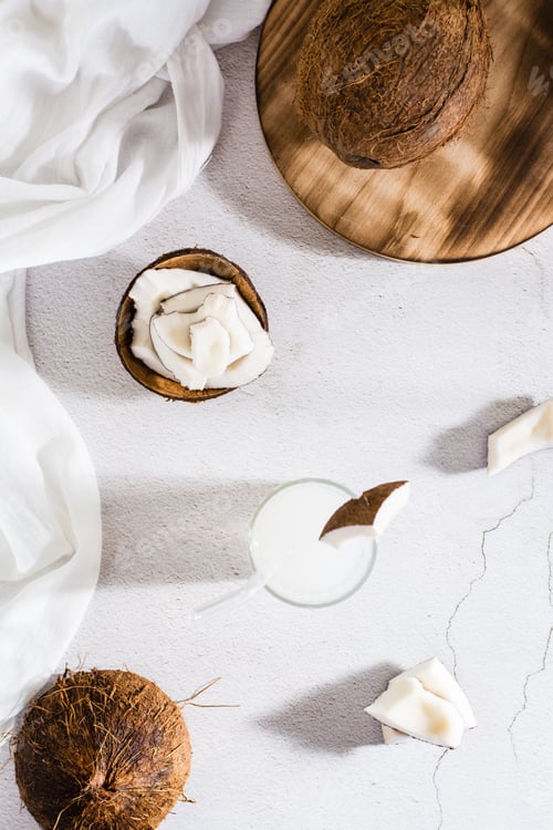 Preview: Coconut milk in a glass with a straw and pieces of tropical fruit on the table. Top and vertical