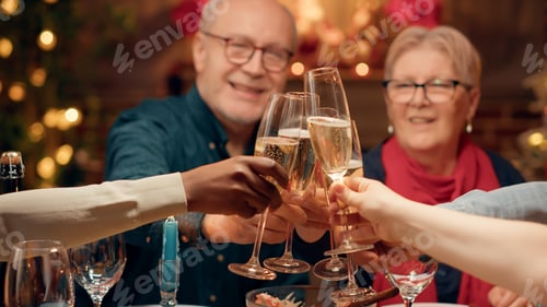 Preview: Festive family clinking champagne glasses while enjoying Christmas dinner at home
