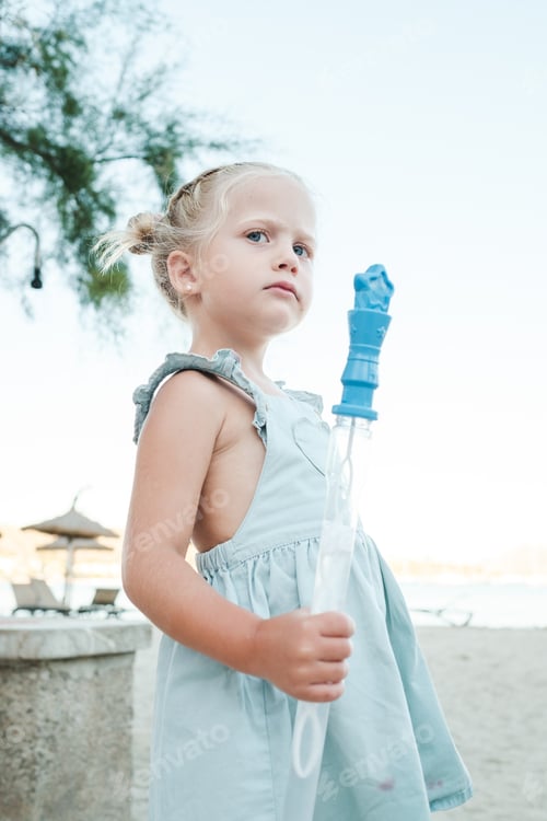 Preview: Little girl with bottle of soap bubbles at beach
