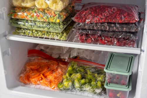 Preview: Plastic bags with different frozen vegetables and berries in refrigerator.