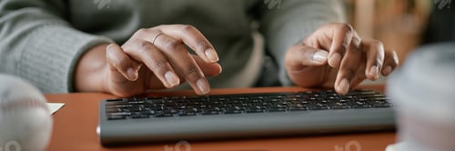 Preview: Header Image of Black Woman Typing on Keyboard While Working Indoors