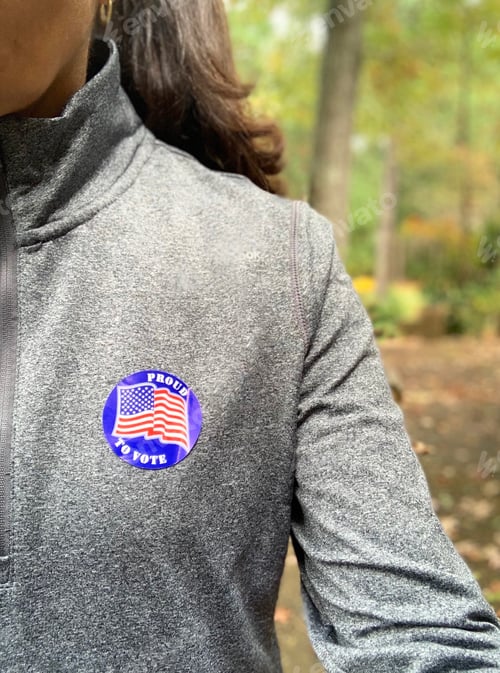 Preview: Latino woman with a Proud to vote sticker on her chest after fulfilling her right & duty as citizen