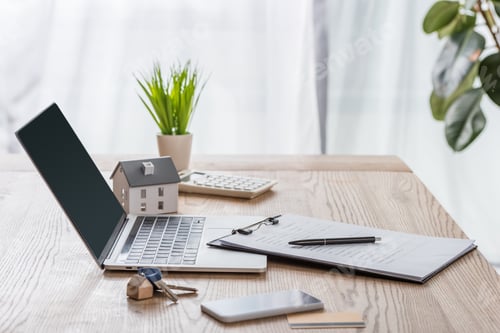 Preview: wooden desk with laptop, smartphone, house keys, clipboard with pen, house model and green plant