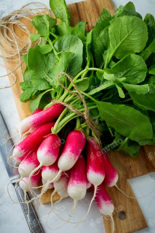 Preview: Bunch of fresh raw ripe young radishes with leaves on a light background. Selective focus