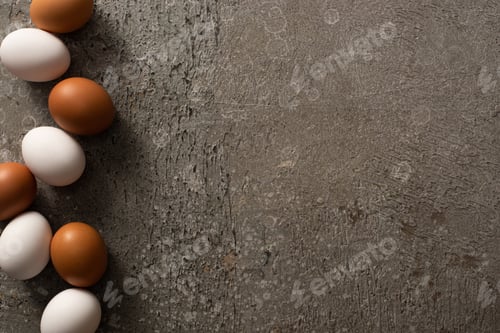 Preview: top view of brown and white chicken eggs on grey textured background