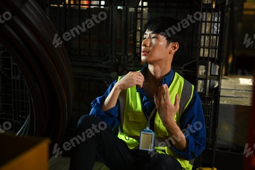 Preview: Exhausted man warehouse worker sitting in on floor feeling tired from hard work and hot temperature