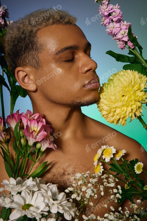 Preview: Confident young man with dyed hair surrounded by vibrant flowers in studio setting