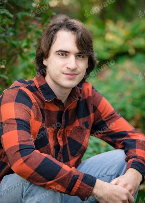 Preview: Portrait of a generation z young man sitting outdoors wearing an orange plaid shirt