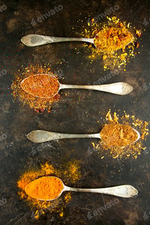 Preview: Types of various spices in spoons on a dark table. Cooking food. Flat lay.