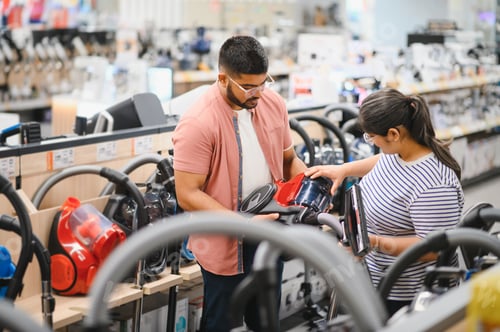 Preview: Young beautiful indian couple buying new vacuum cleaner at tech store