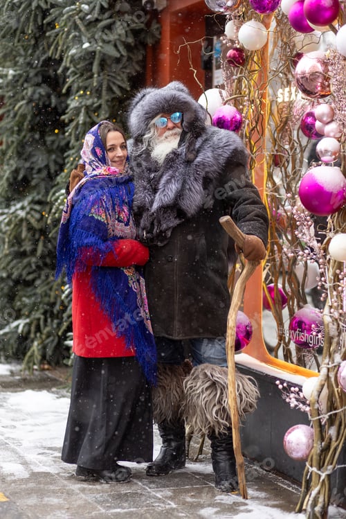 Preview: An elderly gray-haired man with a bushy mustache and beard hugs a young woman with a Slavic scarf