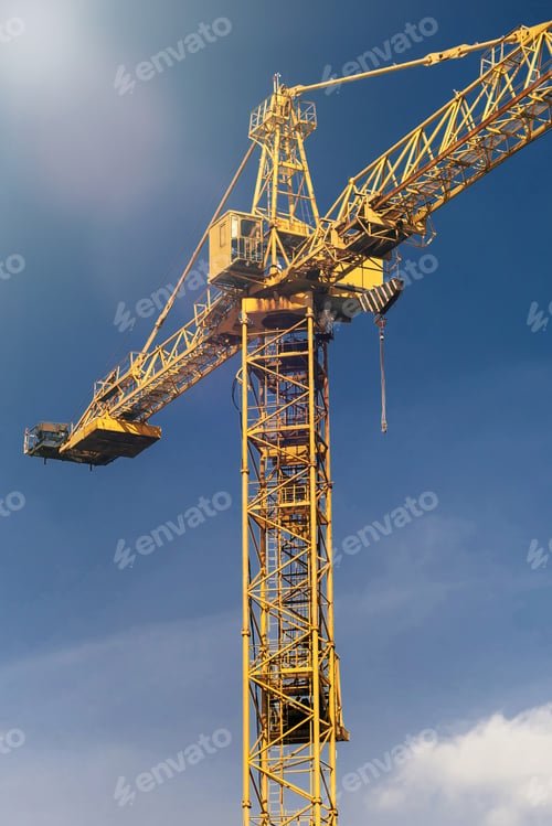 Preview: Construction crane tower in sun light beams on background of blue sky
