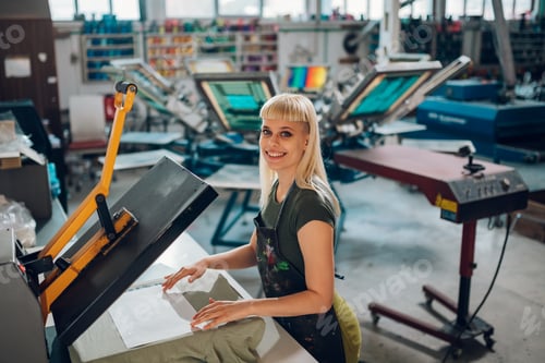 Preview: Portrait of print shop worker using heating press on textile product.