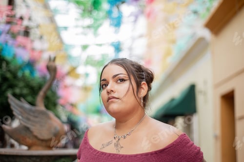 Street portrait of young woman looking at camera with multicolored flags in background. background,