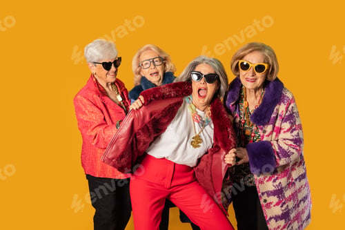 Preview: Group of stylish senior women showing off their fashion on yellow background