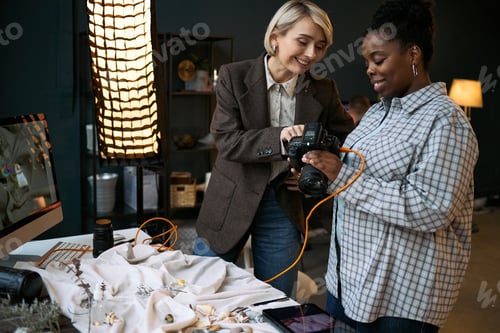 Preview: Caucasian Woman Teaching Young Black Woman Using Digital Camera Indoors