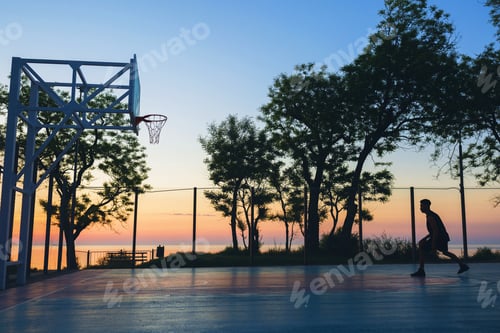 Preview: black man doing sports, playing basketball on sunrise, silhouette