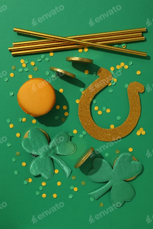 Preview: Golden coins and horseshoe, straws and clover leaves on green background, top view