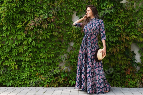 Preview: Gorgeous woman wearing beautiful maxi dress posing against wall with a wild grape