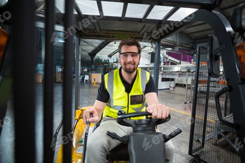 Preview: Portrait of smiling factory worker driving forklift