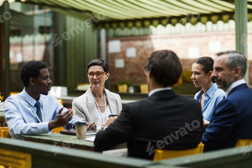 Preview: Diverse Group of Middle Aged Professionals Discussing Business Strategy at Cafe