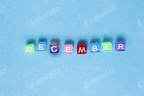 Preview: inscription december made by multicolor plastic cubes on a blue background.
