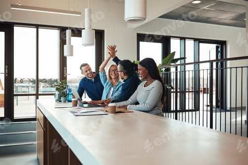 Preview: Two laughing coworkers high fiving together during an office meeting