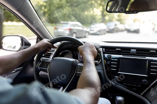 Preview: Cropped of black man driving luxury car, over shoulder shot