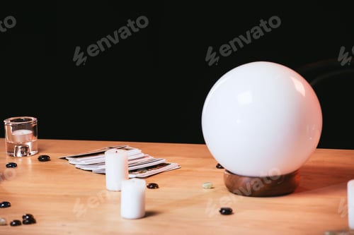 Preview: selective focus of fortune teller near candles on wooden table isolated on black