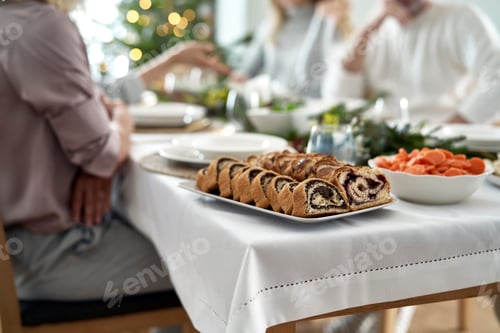 Preview: Poppy seed cake on plate and caucasian family in chatting over the Christmas Eve