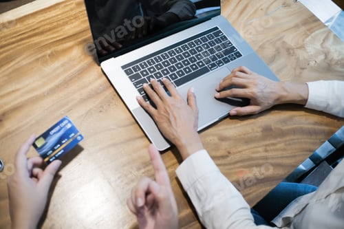 Preview: Woman holding credit card and using laptop computer. Online shopping concept.